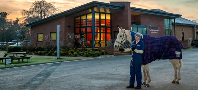 Veterinary surgeon with horse in front of the Equine Hospital reception building