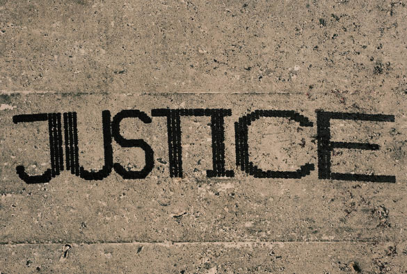 A pavement with black text that reads 'Justice'.