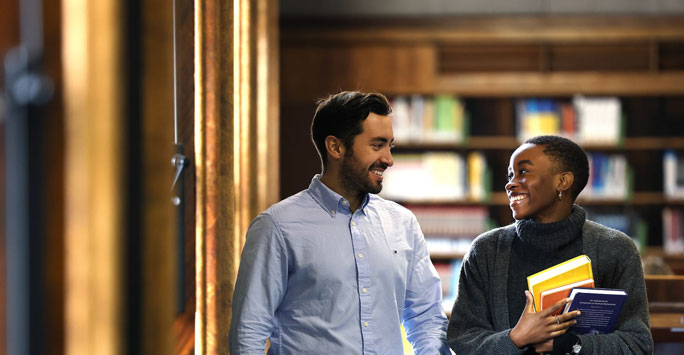 Two students in a library, smiling