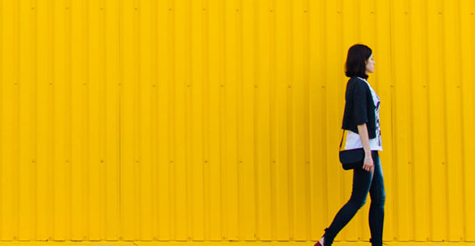 Woman walking against a yellow background