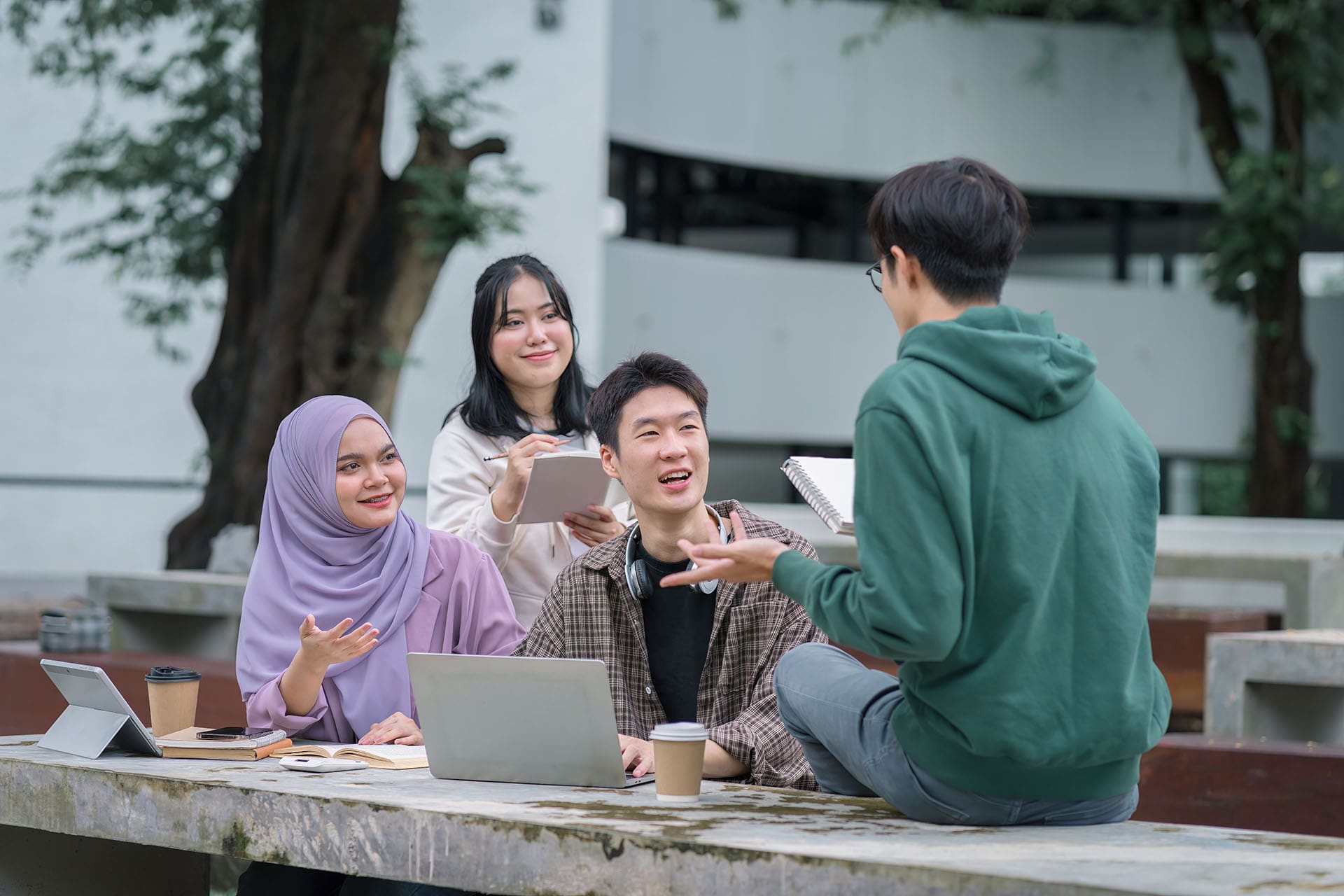 A group of students sitting on a bench and talking together.