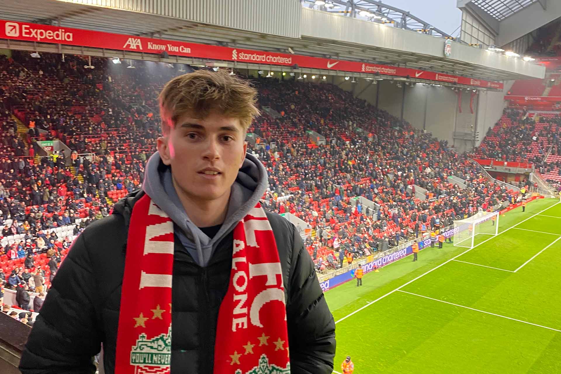 Student Will stands in Anfield stadium, with a full Kop stand visible behind him.