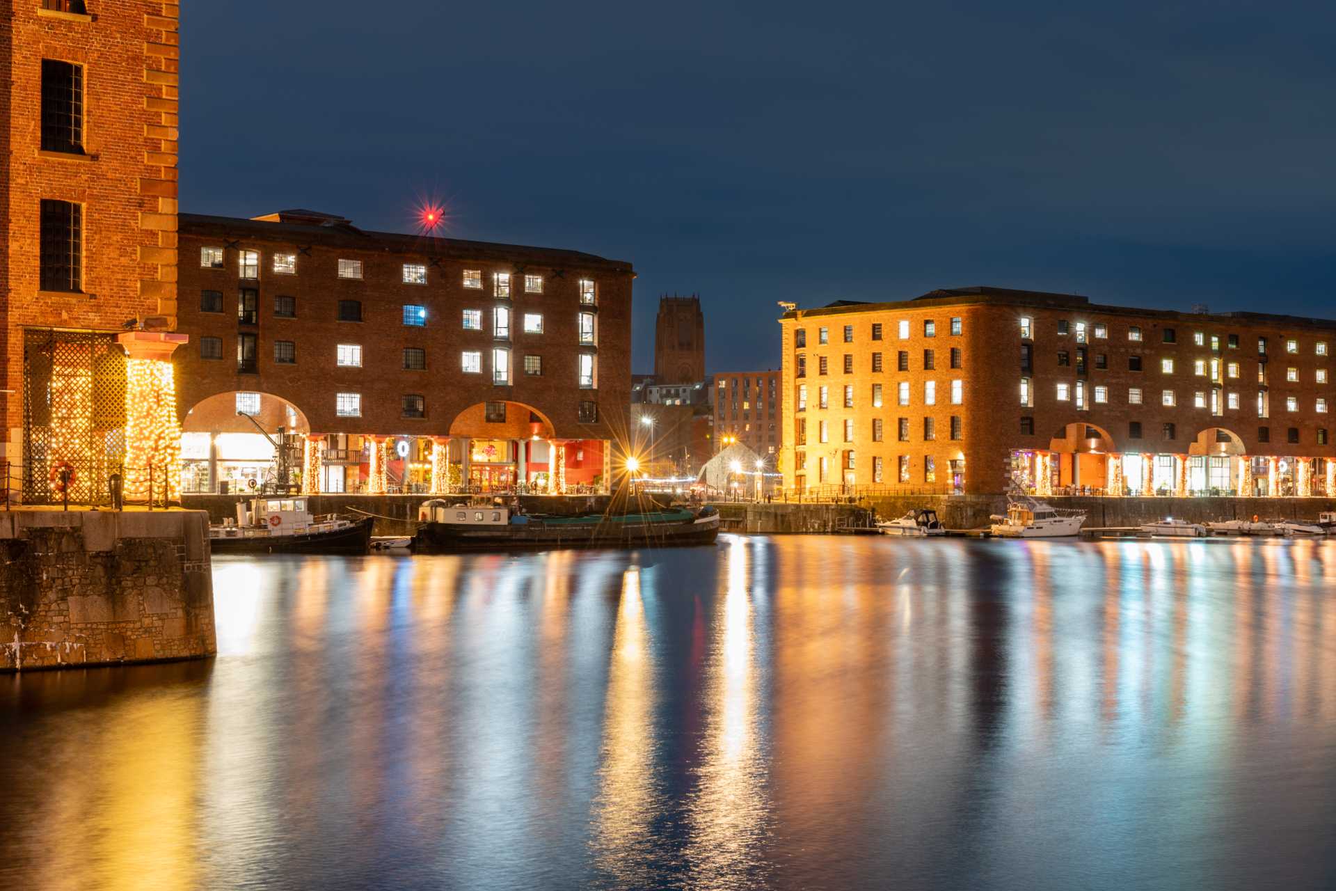 A view of the Albert Dock waterfront in the evening, with lights reflecting on the water.
