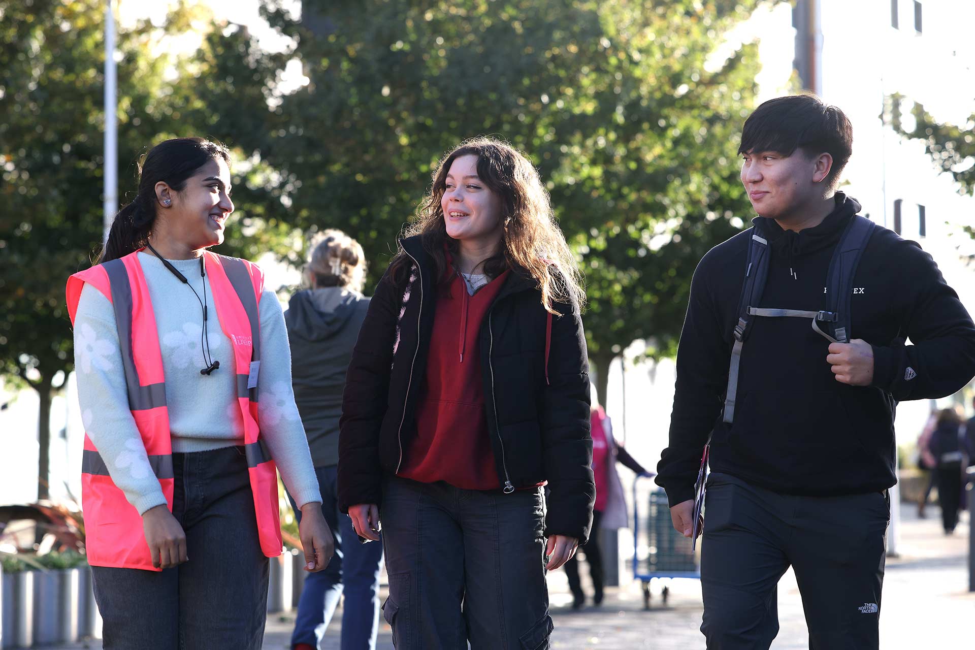 A University of Liverpool ambassador chatting with two students whilst walking through campus