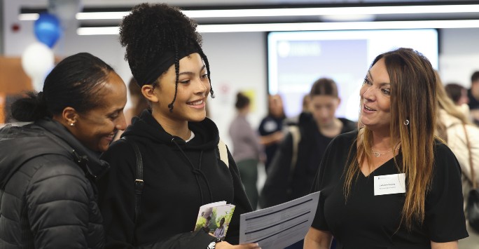 A student with their supporter speaking to a member of University staff on an open day