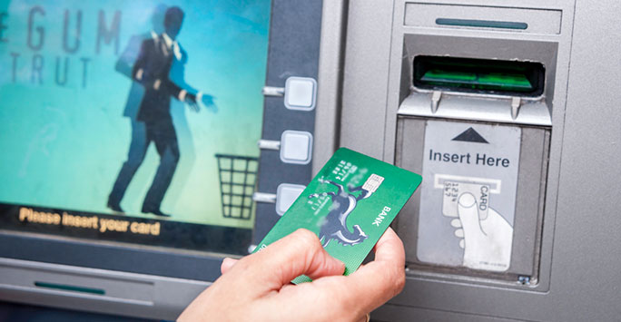 A debit card being inserted into a cash machine to withdraw some cash.