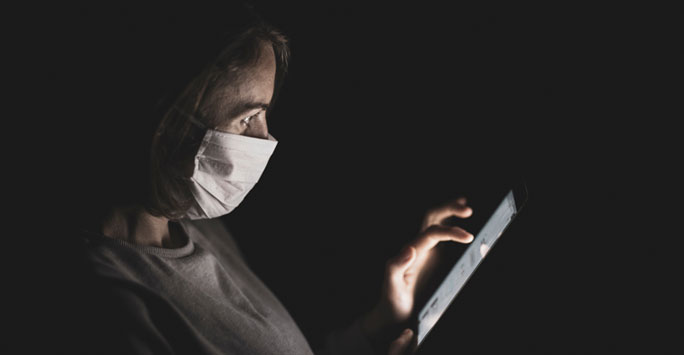 Woman in medical mask using mobile phone