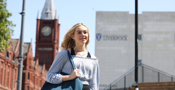 A student smiling with the Victoria Gallery and Museum and Foundation Building in the background